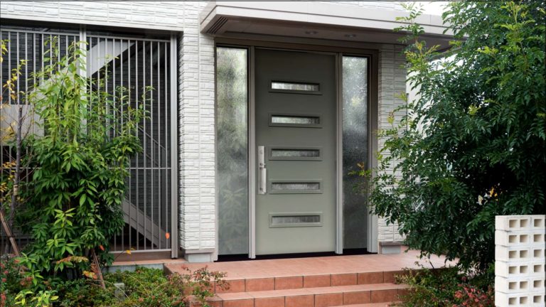 The front entry area of a home with a large green door with glass details