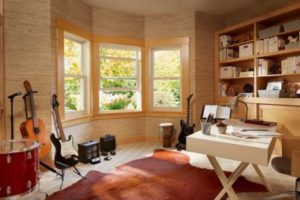 A music room inside a residential home with a bay window and several guitars around the room