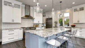 A modern kitchen with white cabinets, natural stone countertops and stainless steel appliances