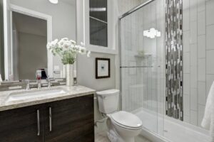 Glass walk-in shower with white subway tiled surround accented with vertical mosaic tile strip in luxury home bathroom. 